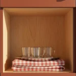 Dettaglio del vano a giorno in rovere dell'armadio Incanto con anta terracotta e maniglia in legno