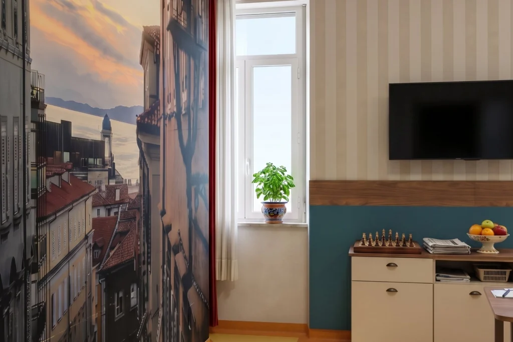 Soggiorno comune con parete decorativa, TV e mobile porta giochi — RSA, progetto Ad Maiores