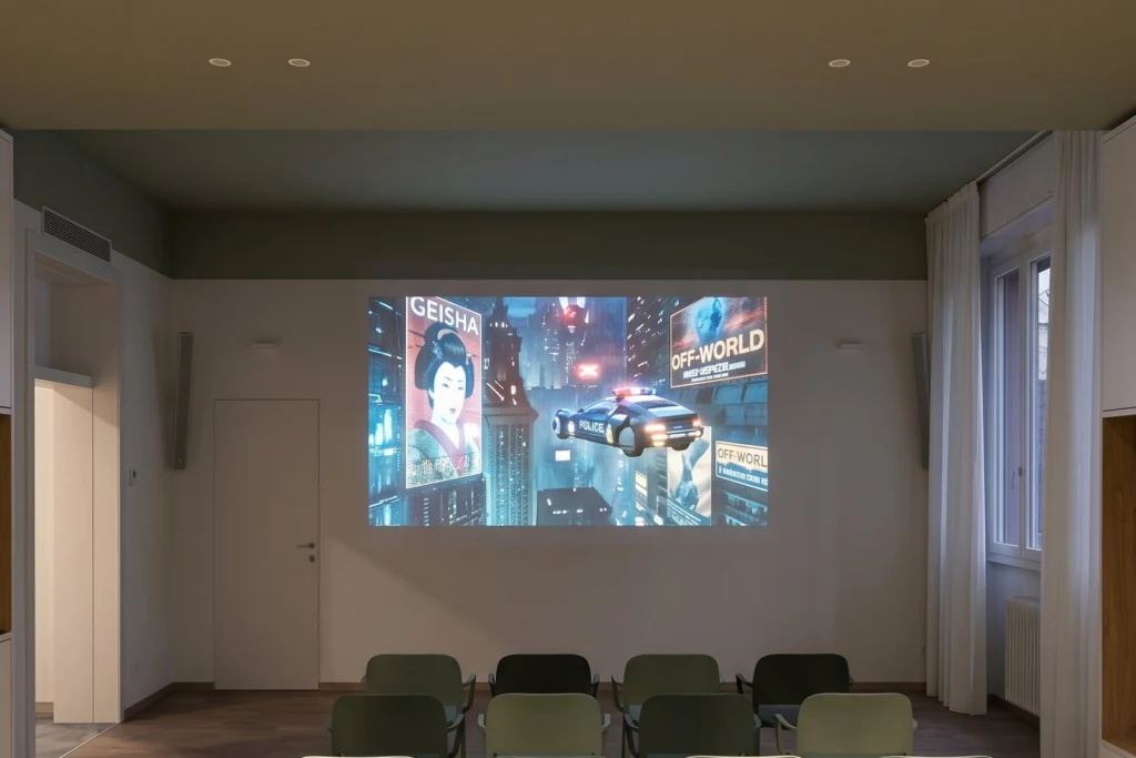 Sala proiezioni con sedute impilabili e schermo a parete — RSA, progetto PCDR