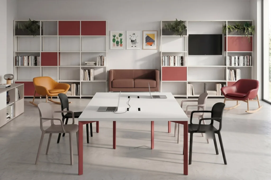 Sala studio comune con libreria modulare, tavolo condiviso e poltroncine — residenza universitaria, progetto Studentati