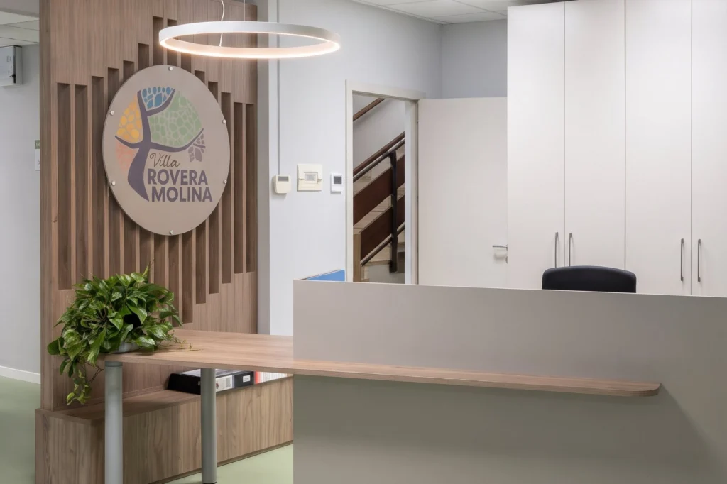 Bancone reception con panca in legno e fioriera integrata — RSA, progetto Villa Rovera Molina