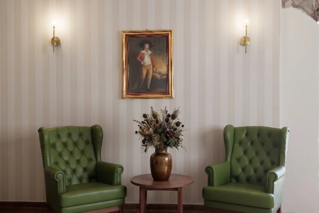 Angolo salotto con poltrone Chesterfield verdi e tavolino tondo — RSA, progetto Villa Spada