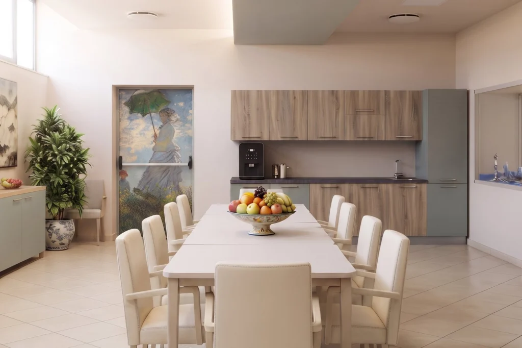 Sala da pranzo con tavolo lungo, sedute imbottite e cucina attrezzata — RSA, progetto Villa Spada